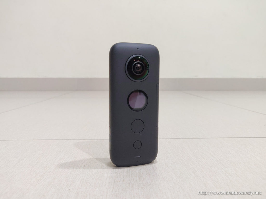The Insta360 One X 5.7K Action camera. On this face is the camera, display screen, shuttle button and power button.